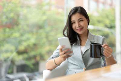 Young woman using mobile phone while sitting on table