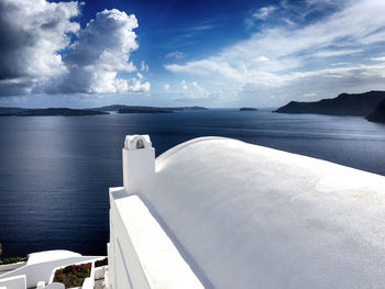 High section of house by seascape against cloudy sky