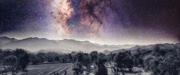 Panoramic view of trees and mountains against sky at night