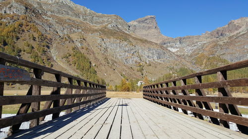 Footpath leading towards mountains against clear sky
