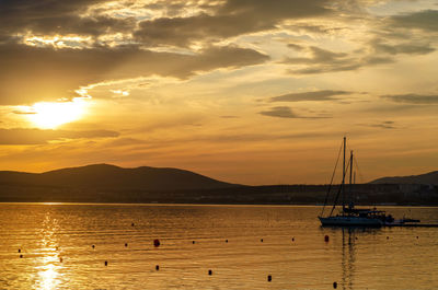 Silhouette sailboats in sea against sky during sunset