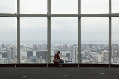 Woman looking through window in city
