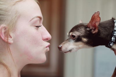 Close-up of young woman kissing chihuahua