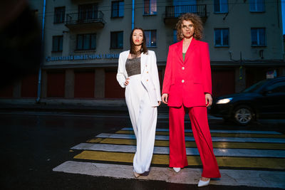 Two beautiful fashionable women posing in the evening on the city street