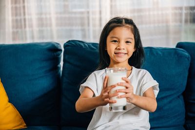 Young woman using mobile phone while sitting on sofa at home