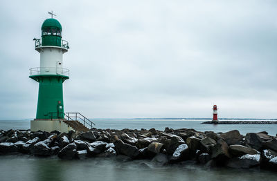 Lighthouse by sea against sky