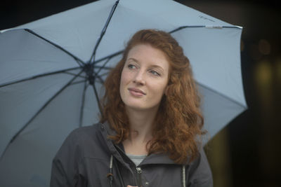 Young woman outside umbrella looking