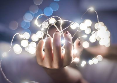 Close-up of woman's hand holding fairy lights