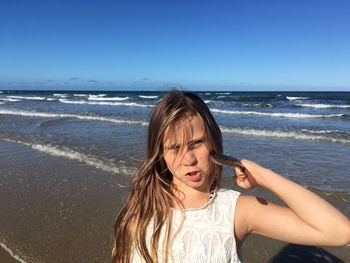 Beautiful woman standing at beach against sky