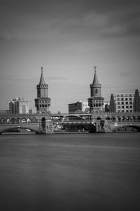 View of buildings at waterfront against cloudy sky