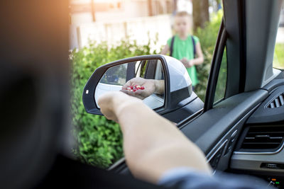 Cropped image of father holding fruits while sitting in car with daughter standing outdoors