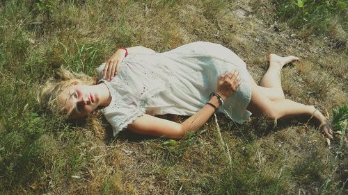 Portrait of young woman lying on field