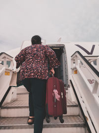 Rear view of woman standing on road against sky