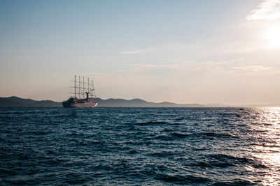 Sailboat sailing on sea against sky during sunset