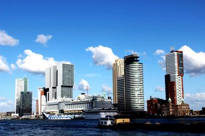 Cruise ship on sea by modern buildings against sky