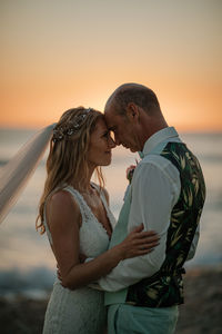 Couple kissing against sky during sunset