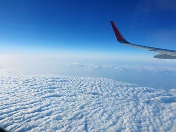 Aerial view of snowcapped mountain against blue sky