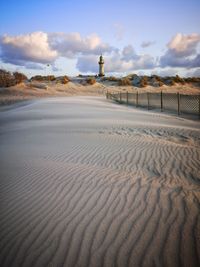 View of sand dunes at beach against sky