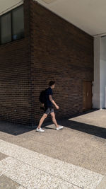 Full length of man on footpath against wall