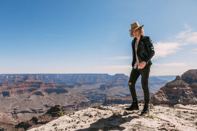 Man standing on rock against sky