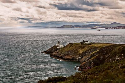 Scenic view of sea and mountains against cloudy sky