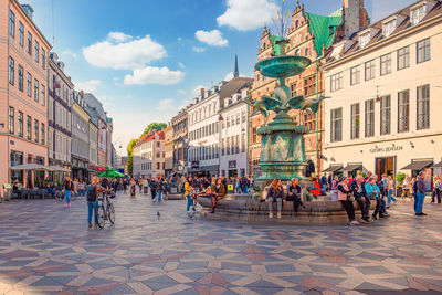 People walk and sit  on amager square amagertorv at the strøget pedestrian zone. copenhagen, denmark