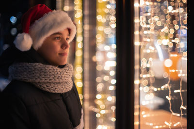 Smiling boy looking inside store from outdoors at night