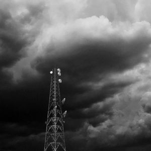 Low angle view of communications tower against cloudy sky