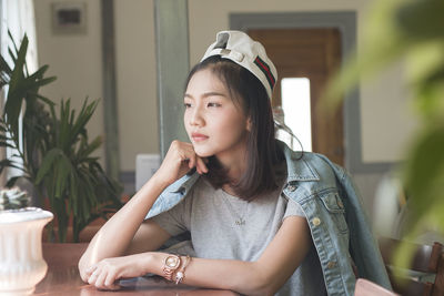 Thoughtful woman with hand on chin sitting at table