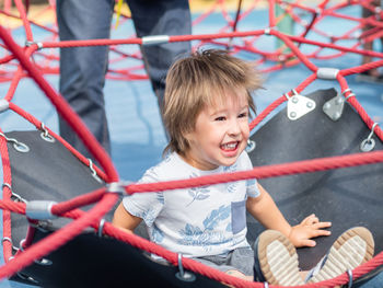 Laughing toddler is jumping on playground. sport equipment for children physical development. 