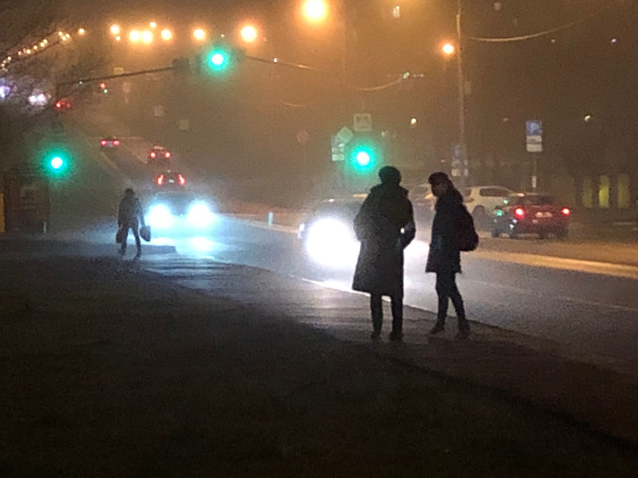 PEOPLE WALKING ON ILLUMINATED ROAD IN CITY AT NIGHT