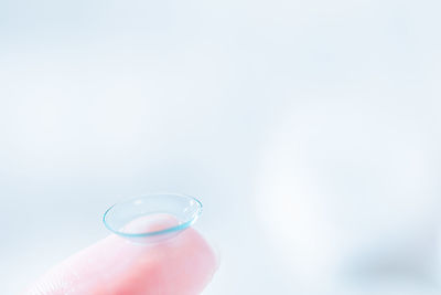 Close-up of hand holding glass over white background