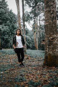 Full length portrait of woman standing in forest