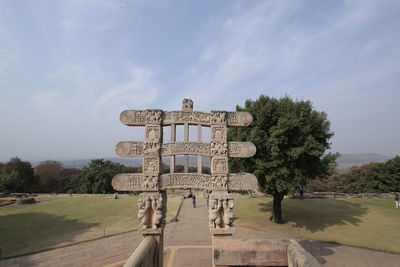 View of cross on landscape against cloudy sky