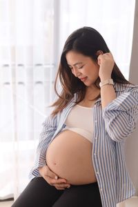 Smiling pregnant woman sitting at home