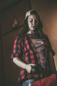 Low angle view of woman holding gun and standing at home