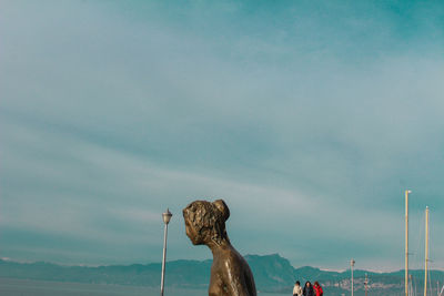 Statue by sea against sky