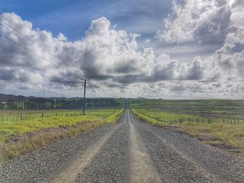 Road amidst field against sky