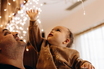 Father and son playing with lights garland. dad holds his baby boy on arms. turkish ethnicity