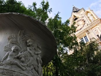 Low angle view of statue by building against sky