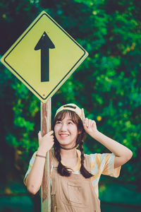 Portrait of young woman by road sign