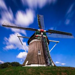 Low angle view of traditional windmill on field against sky