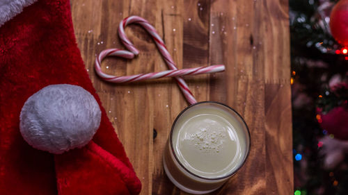 Close-up of drink glass with candy canes and santa hat on table