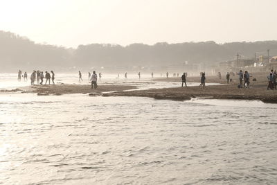 People on beach against clear sky