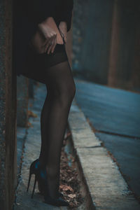 Low section of woman adjusting stockings outdoors