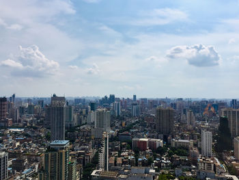 Aerial view of modern buildings in modern city against cloudy sky