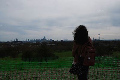 Rear view of woman standing on field against sky