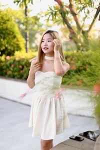 Portrait of young woman standing against trees