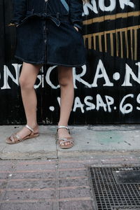 Low section of woman standing on footpath