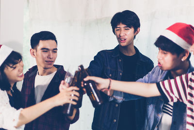 Friends toasting beer bottles during celebration at home